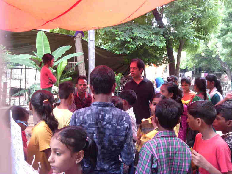 Rakesh Raman explaining the benefits of modern alternative education to people in a street of Delhi. Click the photo to know the details of the education awareness campaigns that he is running.