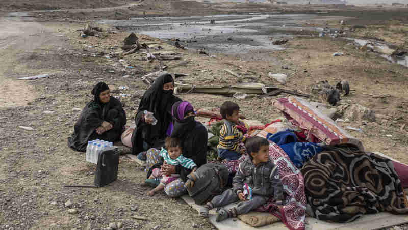 A family displaced by fighting in the village of Shora, 25 kilometres south of Mosul, wait by the roadside at an army checkpoint on the outskirts of Qayyarah. Photo: UNHCR / Ivor Prickett