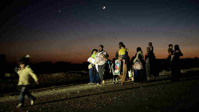 Iraqi civilians, who fled fighting in the city of Mosul, walk lit up by Iraqi special forces armoured vehicles, as they head to camps housing displaced people on November 2, 2016 in Bazwaia, Iraq. Photo: UNICEF