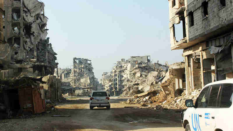 UN vehicles travel along a road lined with remnants of destroyed buildings, Homs, Syria. (file) Photo: UNICEF / UNI178367/ Tiku (file photo)