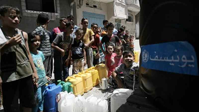 On 23 August 2014 children queue to fill jerrycans and other containers with water, at a filling station in Nuseirat, in the central Gaza Strip. Photo: UNICEF
