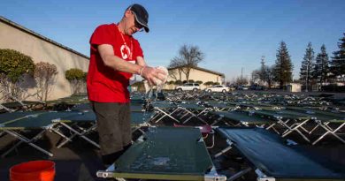 A Red Cross volunteer cleans cots outside of the Red Cross Silver Dollar Fairgrounds shelter in Chico, California.