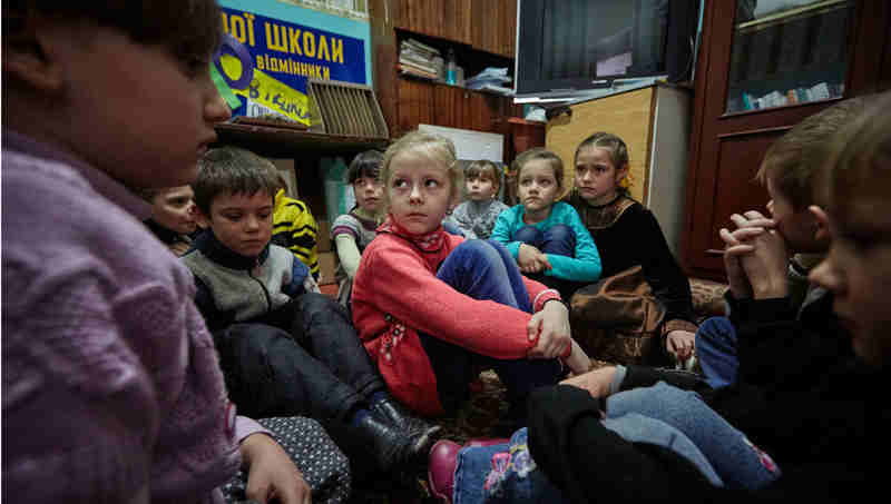 On 13 February 2017, first-grade students in eastern Ukraine, including 6-year-old Sasha (in red sweater), participate in a drill to practice their response to a shelling. Photo: UNICEF / UN053119 / Zmey