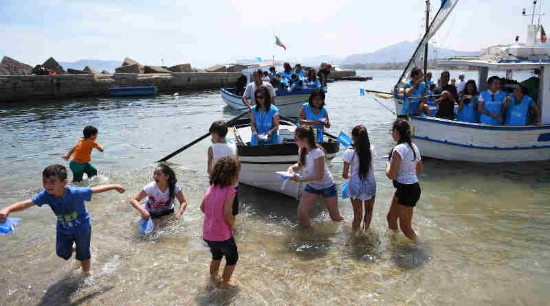 Italian Coastguard, children, volunteers and officials take part in a symbolic rescue of paper boats to send a message to the G7 leaders to take action to safeguard children on the move off a beach in Palermo, Italy, on Thursday, May 25, 2017.