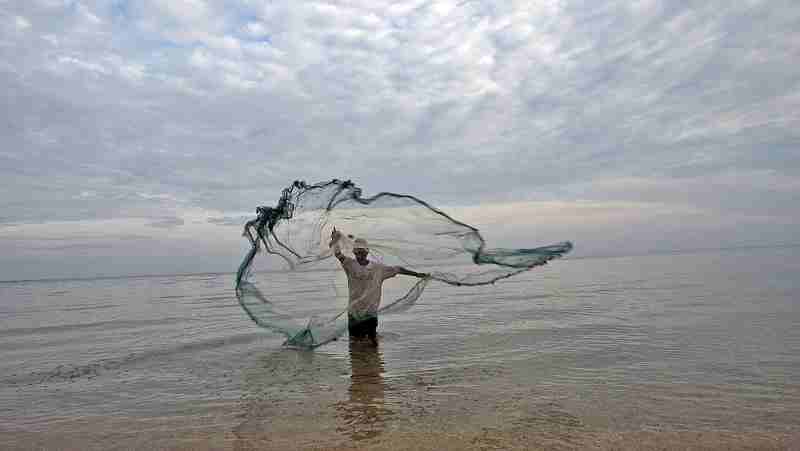 Fisherman in Timor Leste casts net in the water to catch small fish. UN Photo/Martine Perret