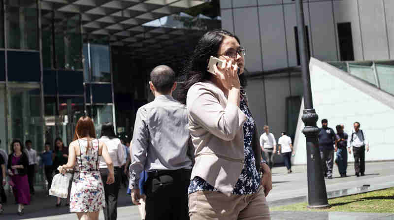 A woman speaks on the phone as she walks to work in Singapore. Photo: ILO/Giorgio Taraschi