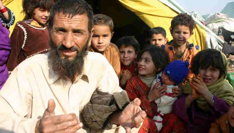 Afghan refugees sit outside their tent in Islamabad, Pakistan. Photo: UNHCR/A. Shahzad