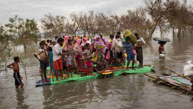 Rohingya refugees, including infants and children, on a makeshift raft made of logs, bamboo poles and jerrycans are brought to shore through the mangroves after they crossed the Naf River, which demarcates the border between Myanmar and Bangladesh, Sunday 12 November 2017. Photo: UNICEF