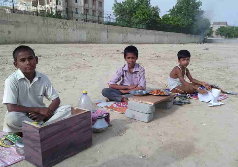 Young children forced by parents to sell eatables outside a school building in New Delhi, India. Click the photo to know the details.