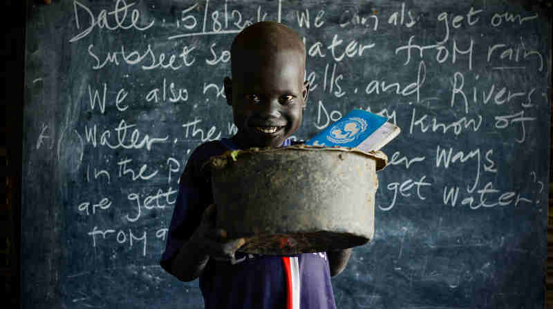 On 15 August 2016 in the Bentiu Protection of Civilians site (POC) in Unity State, Maet, 6, carries an old broken saucepan with a hole in it to school so he has something to sit on during class. Photo: UNICEF