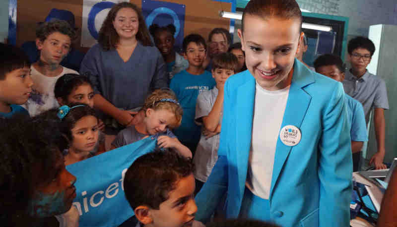 UNICEF supporter Millie Bobby Brown on the set of a video produced for World Children's Day 2018 on 24 August 2018 in New York City in the United States of America. Actor Millie Bobby Brown has teamed up with UNICEF Goodwill Ambassadors Orlando Bloom, Liam Neeson and Lilly Singh; singer-songwriter Dua Lipa and performance artists the Blue Man Group, in a new video released by UNICEF ahead of World Children’s Day, celebrated on 20 November 2018. The short video shows the 14 year-old star – who has symbolically changed her name to Millie Bobby ‘Blue’ to mark the occasion – overseeing a global ‘go blue’ operation. Alongside her team of young helpers, Millie calls on fellow UNICEF Goodwill Ambassadors and supporters to join her in going blue – by wearing or displaying the colour blue – in support of children’s rights. As the story unfolds, viewers see the stars responding to Millie’s call while going about their daily lives. Liam Neeson bakes blue cupcakes while reenacting a famous scene from his cult-hit Taken, Dua is in studio re-recording the lyrics of her global hit Be The One from red to blue, Orlando is on a film set working under his new name – Orlando ‘Bluem’ – and Lilly is at home making ‘blunicorn’ smoothies. UNICEF’s annual World Children’s Day is commemorated each year on 20 November and marks the anniversary of the adoption of the Convention on the Rights of the Child. The global day raises awareness and vital funds for the millions of children who are unschooled, unprotected and uprooted. This year, UNICEF is inviting the public to go online and sign its global petition asking for leaders to commit to fulfilling the rights of every child now and for future generations, and to Go Blue for every child by doing or wearing something blue on 20 November.