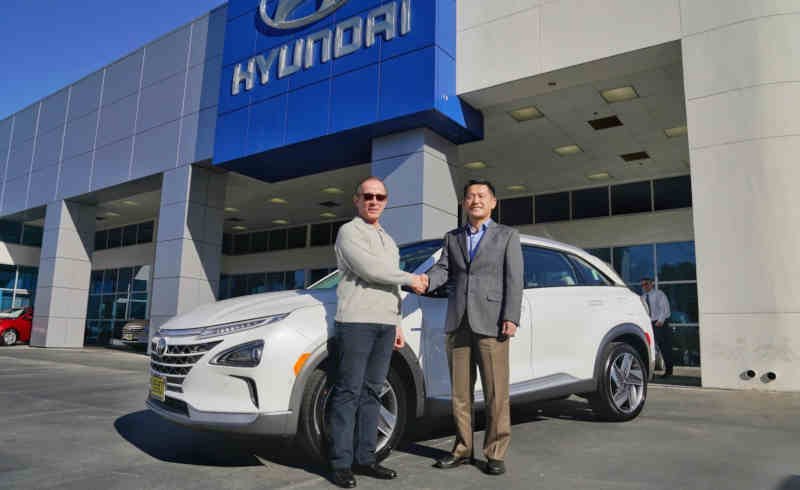 Yong-woo (William) Lee, president and CEO of Hyundai Motor North America, congratulates Tom Hochrad of Ventura, Calif., the first customer to receive the all-new Hyundai Nexo.