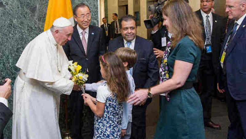 Pope Francis is welcomed by Secretary-General Ban Ki-moon and receives flower bouquets from children of UN staff members at the start of his visit to UN Headquarters (file photo). UN Photo / Mark Garten