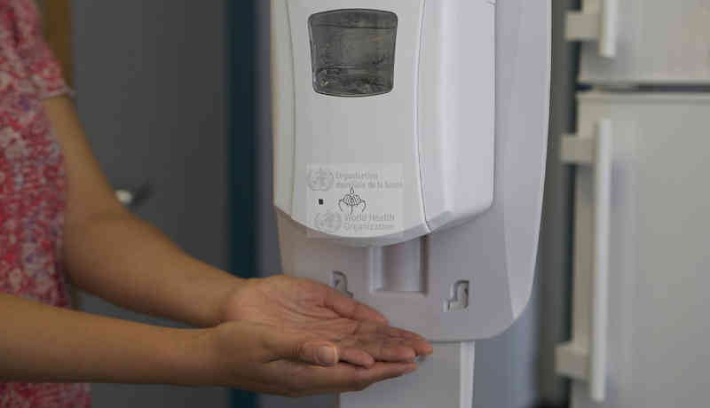 A health worker sanitizes her hands before putting on a mask. Photo: WHO (Representational Image)