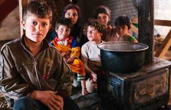 Syria refugees Adel and his siblings try to keep warm by the fire inside their makeshift home in the Bekaa Valley, Lebanon
