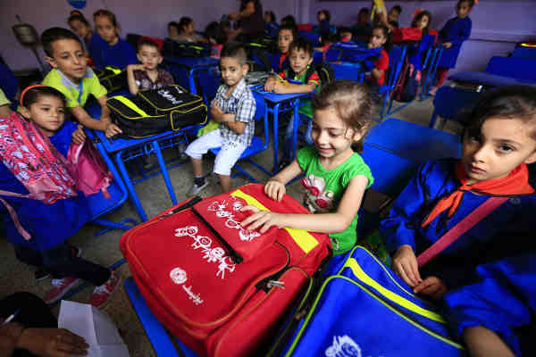 On 13 September 2015 in Syria, 6-year-old Fatima, in Grade 1, smiles after receiving her new schoolbag, on her first day at Nazem Atrash Primary School in Homs City. Photo credit: UNICEF / Sanadiki