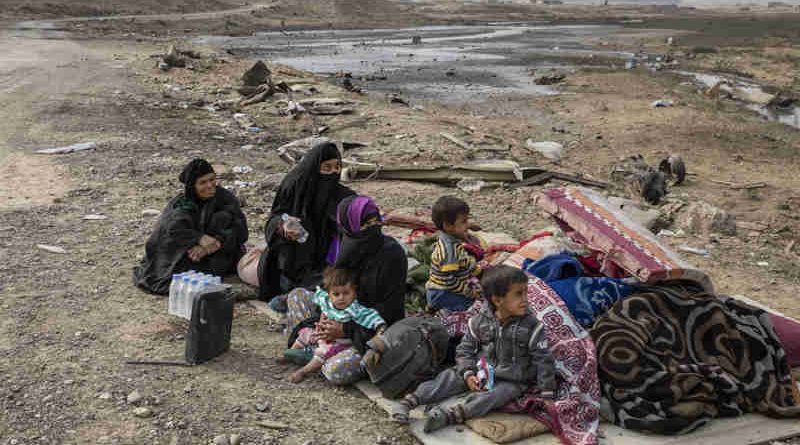 A family displaced by fighting in the village of Shora, 25 kilometres south of Mosul, wait by the roadside at an army checkpoint on the outskirts of Qayyarah. Photo: UNHCR / Ivor Prickett