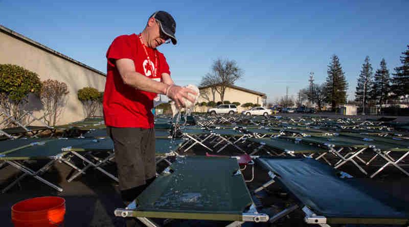 A Red Cross volunteer cleans cots outside of the Red Cross Silver Dollar Fairgrounds shelter in Chico, California.