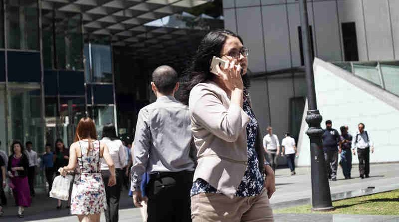 A woman speaks on the phone as she walks to work in Singapore. Photo: ILO/Giorgio Taraschi (Representational photo)