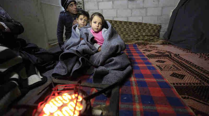 A Syrian family tries to keep warm in this unfinished building in the informal settlement of Al-Khalidia Al-Khamisa in Homs. UNICEF/Sanadiki (file)