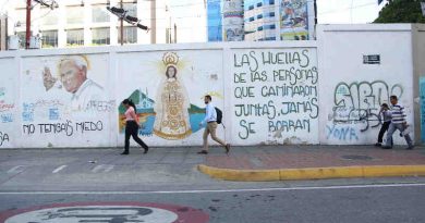 3 June 2019: People pass in front of street graffiti in Caracas, Venezuela. The text reads: “The footprints of those who travel together will never be erased.” Photo: UNICEF